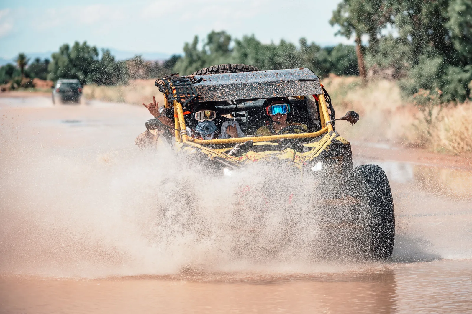 Buggy cruzando un charco de agua entre salpicaduras junto a un oasis de palmeras en Marruecos