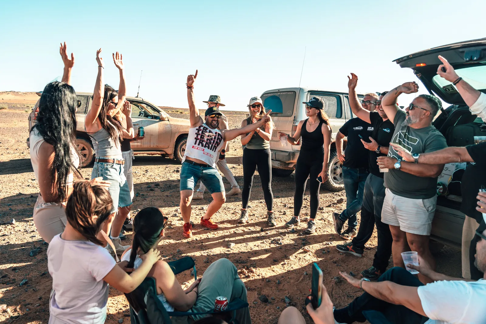 Grupo de viajeros bailando y celebrando junto a los 4x4 en el desierto de Marruecos