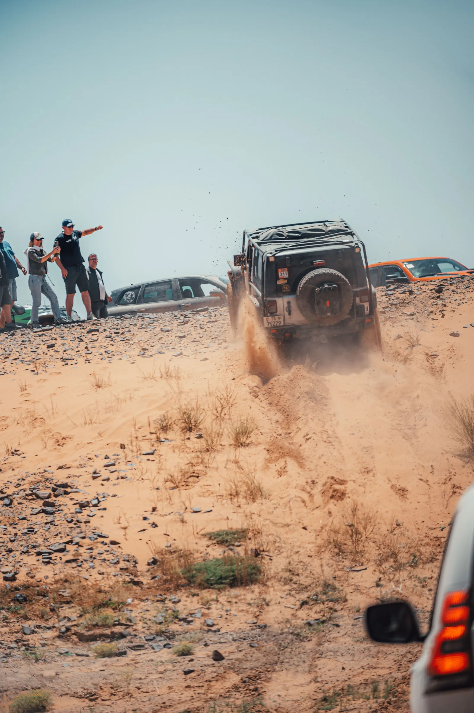 Land Rover Defender superando una duna de arena mientras el grupo observa la maniobra 4x4 en Marruecos