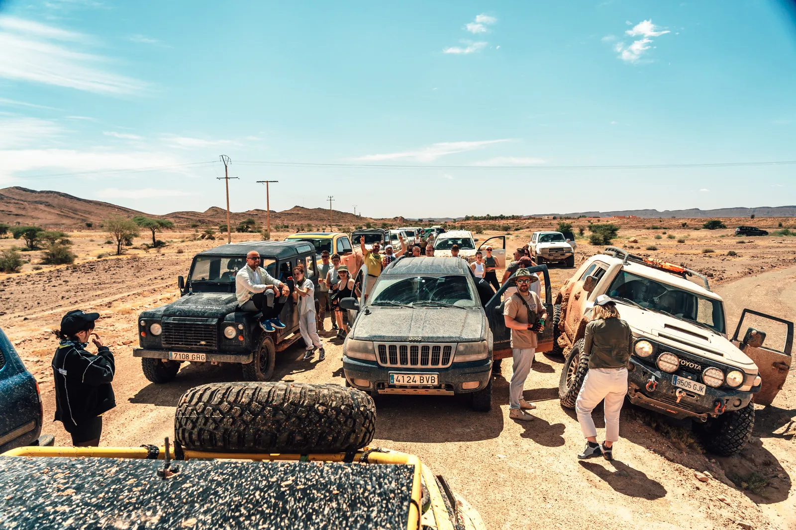 Grupo de viajeros y vehículos 4x4 parados junto a un oasis durante una ruta de aventura por Marruecos