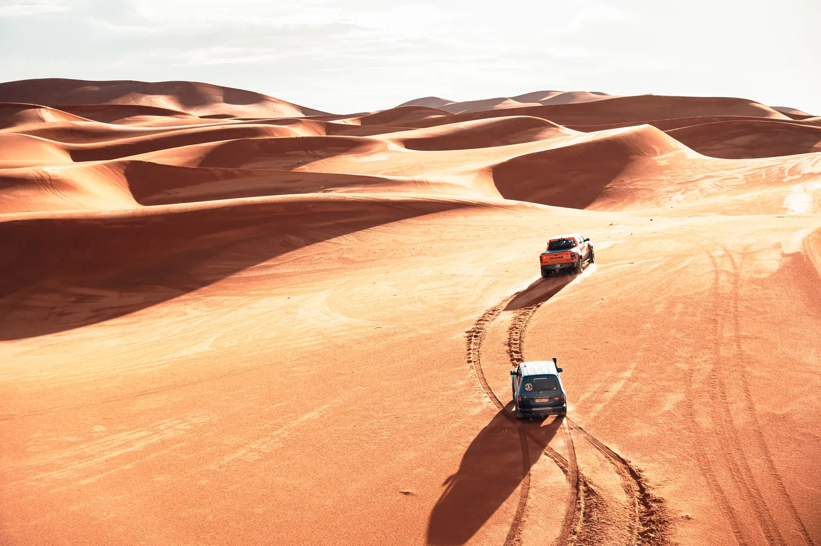 Vista aérea de dos 4x4 recorriendo un mar de dunas en el desierto de Marruecos